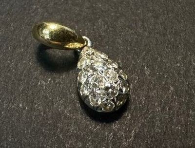 a silver and gold pendant on a black surface