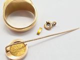a close up of a gold ring with a gold coin and a gold pin