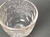 a clear glass with a pattern on it sitting on a saucer