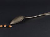 an old spoon and two small pills on a black surface