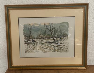 tableau représentant un paysage enneigé, dans un cadre doré, posé sur une table en bois