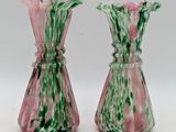 pair of pink and green glass vases sitting on a white surface