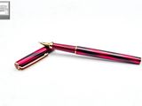 the pen is red with gold trim and has a gold tip