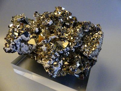 des cristaux dorés et argentés posés sur un support métallique, sur une surface blanche