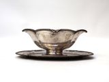 an antique silver plate with a saucer on it on a white surface