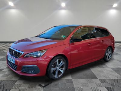 une voiture rouge est garée dans une pièce au sol en damier
