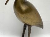 statue en laiton représentant un oiseau au long bec, sur fond blanc