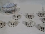 de nombreuses tasses et soucoupes posées sur une table, avec une théière