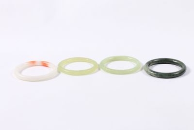 trois bagues en jade vert et blanc sur un fond blanc