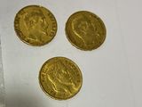 three gold coins sitting next to each other on a white surface