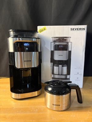 a black and silver coffee maker sitting on top of a wooden table