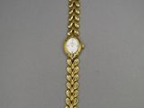a gold bracelet watch with a chain around it