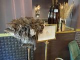 a vase with feathers on a stand in a room