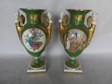 two green vases with pictures on them sitting on a table