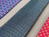 trois cravates de couleurs différentes sont alignées sur une surface blanche