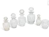 six clear glass perfume bottles lined up on top of each other