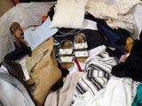 a pile of clothes and shoes on a bed