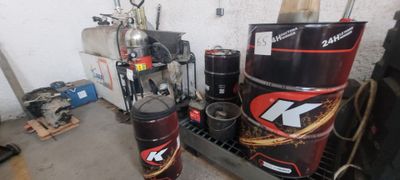 Plusieurs bidons d'huile moteur sont empilés sur un rayonnage dans un garage