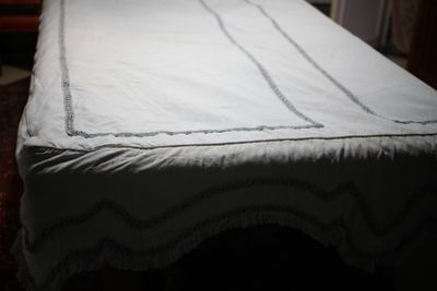 un lit recouvert d'un drap blanc dans une pièce sombre