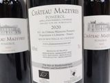 three bottles of red wine are lined up on a table