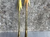 une paire de flèches en laiton posées sur une surface métallique, à côté d'un rocher