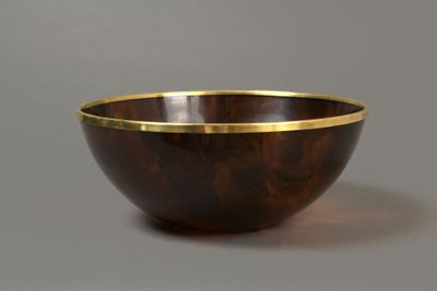 a wooden bowl with a gold rim sits on a gray surface
