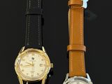 two watches sitting next to each other on a black surface