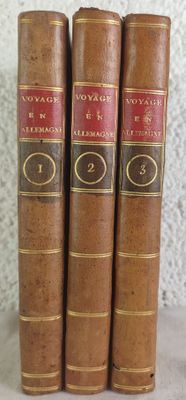 three old books are lined up on a shelf next to a wall