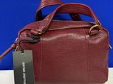 a red handbag with a tag on it sitting on a table