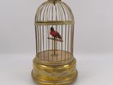 un oiseau doré dans une cage posée sur une table blanche