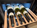 bottles of wine sit in a wine cooler in a kitchen