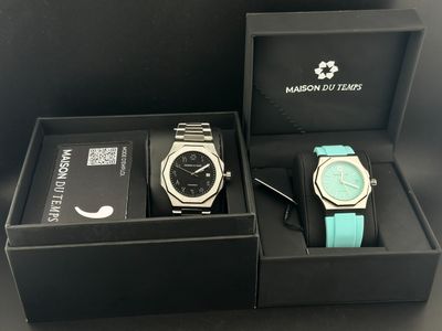 deux montres dans un coffret posé sur une table noire