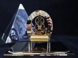 a gold clock on a black table with a blue background