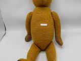 un ours en peluche marron assis sur une surface blanche