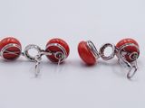 two pairs of red and silver earrings sitting on top of a white surface
