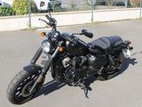 a black motorcycle parked in a parking lot next to a fence