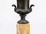 un vase noir posé sur un socle en marbre, sur fond blanc