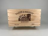 La caisse en bois, posée sur une table, contient une bouteille de vin.