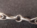 a close up of a silver bracelet on a black surface