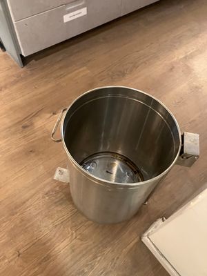 a large metal bucket sitting on the floor next to a box