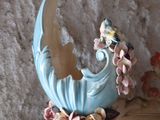 a blue vase with a bird on top of it on a table