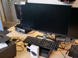 un bureau d'ordinateur équipé de deux écrans, d'un clavier et d'une imprimante