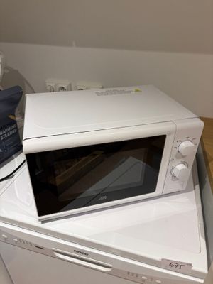 un micro-ondes posé sur une machine à laver et un sèche-linge