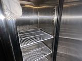 an empty stainless steel refrigerator with a fan in the corner