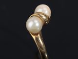 a close up of a gold ring with two pearls on it