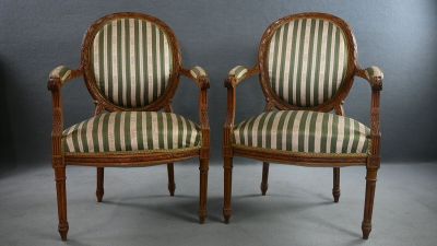 deux chaises avec des accoudoirs rembourrés à rayures et des pieds en bois