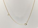 a gold chain necklace with a small circle on a white mannequin