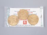 three gold coins in a plastic bag on top of a table