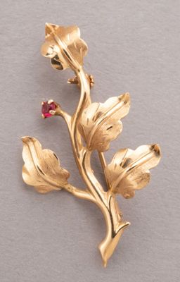 an image of a gold flower brooch with a red stone