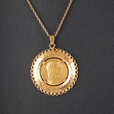 un pendentif en forme de pièce d'or représentant le visage d'une femme